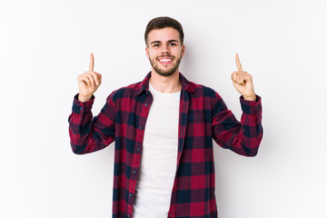 Young caucasian man posing in a white background isolated indicates with both fore fingers up...