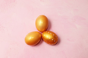 Decorated golden and pink easter eggs on pastel marble background. Minimal holiday concept. Happy easter background. Creative painting of eggs, place for text, postcard, banner for the screen.