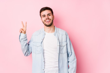 Young caucasian business man posing in a white background isolated joyful and carefree showing a peace symbol with fingers.< mixto >