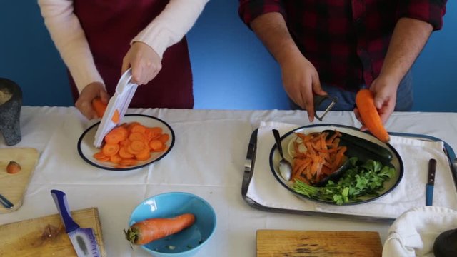 Close up of chopping carrot with mandolin slicer and peeler