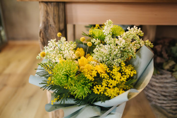 Spring bouquet with yellow tulips and white lilacby the wooden table