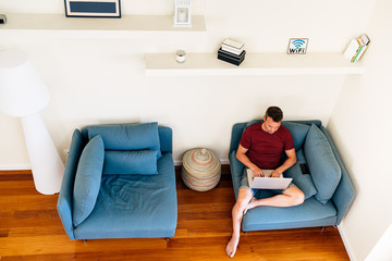 man typing on smartphone while resting at home with laptop