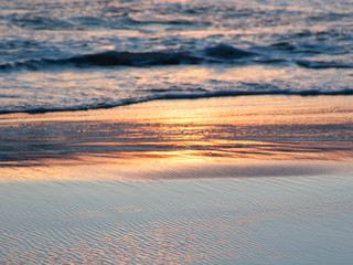 Sea waves and wet sand at sunset