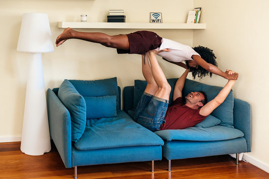 Overjoyed multiethnic couple having fun together in living room - Powered by Adobe