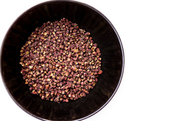 Scented Sichuan pepper in  the black bowl on the white table isolated image. Sichuan pepper or Chinese pepper or Timur or Nepali pepper is very popular in cuisines of Tibet, Bhutan, Nepal, Thailand.