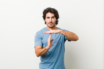 Young handsome man against a white background showing a timeout gesture.