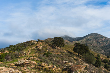 Quiet mountain landscape with trail and mountain peaks with clouds