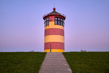 Lighthouse on a dyke in nature near Pilsum. Famous landmark at Krummhoern, North Sea