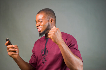 young handsome african boy feels overwhelm bout what he saw on his mobile phone. © Vic Josh