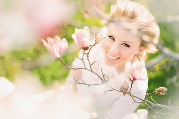 happy young woman smiling underneath a pink blossom tree