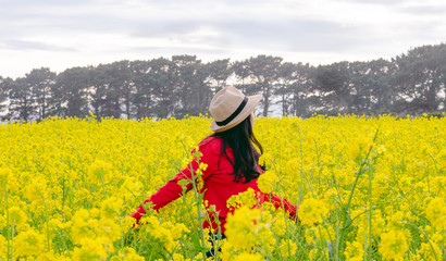 Woman in red sweater and hat on natural yellow flower background. Concept of spring
