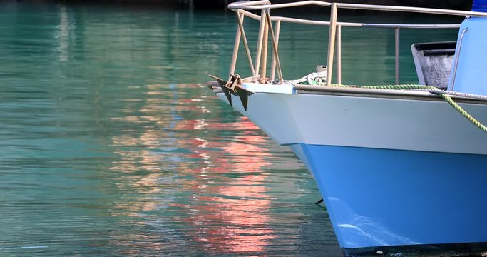 Yacht prow anchored  at port in calm and colorful water. Boat prow with rope.