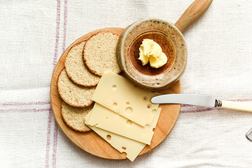 Cheese and biscuits snack of oat cakes with butter and emmental cheese on a board