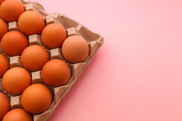 Brown cage free chicken eggs in carton, close up on pink background. easter card