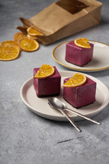 raw currant cheesecake a square cake with a slice of dried orange on a gray concrete background
