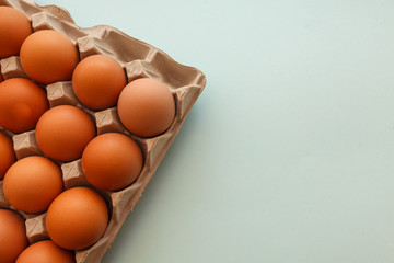 Brown cage free chicken eggs in carton, close up on blue background. easter card