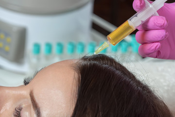 Cosmetologist does prp therapy against hair loss of a beautiful woman in a beauty salon....