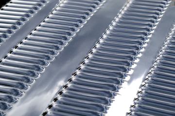 Fototapeta premium Repeating rows of cooling holes on a chrome metal surface of the hood of a modern car.