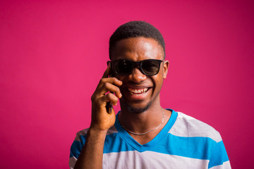 a young african man wearing strips cloth isolated over pink background feeling excited about the call he his receiving on his smart phone