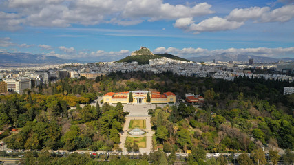 Fototapeta na wymiar Aerial drone photo of renovated public neoclassic building of Zappeion used for events and meetings in the National Gardens of Athens and Lycabettus hill aligned at the background, Greece