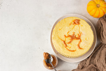 Pumpkin cheesecake with caramel sauce, light grey stone background. Selective focus. Top view.