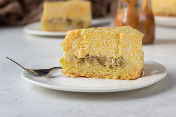 Plate with slice of pumpkin cheesecake and with caramel sauce, light grey stone background. Selective focus. 