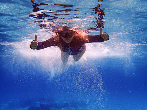 Woman snorkeling in sea giving the thumbs up sign, Greece