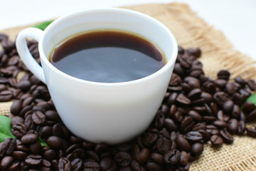 Coffee beans, accompanied by cup of hot coffee
