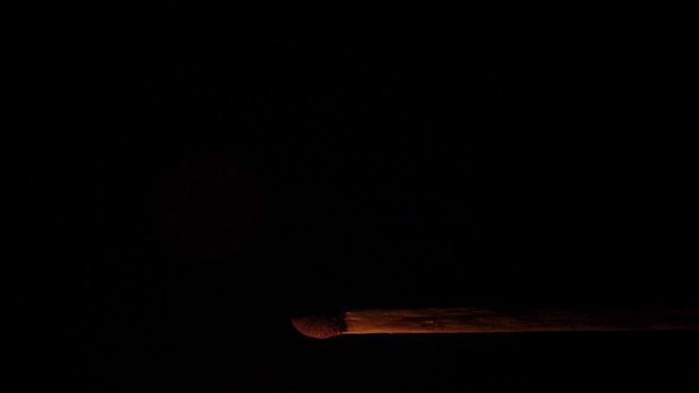 Footage of a match in a pitch dark room being lightened up and burns out