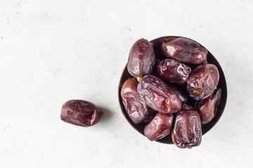 Coconut shell with organic medjool dates on a light grey concrete background. Selective focus, copy space.