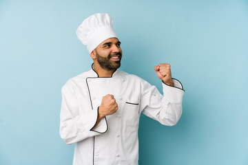 Young latin chef man isolated raising fist after a victory, winner concept.