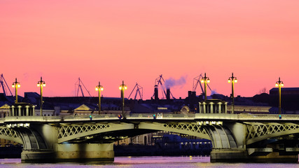 Illuminated bridge over the Neva at sunset on a frosty evening