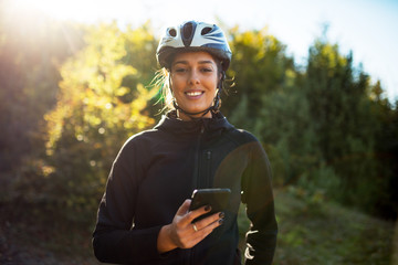 Portrait of beautiful female cyclist using phone