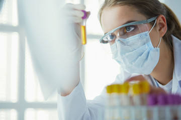Portrait of pretty female laboratory assistant analyzing a blood sample at hospital