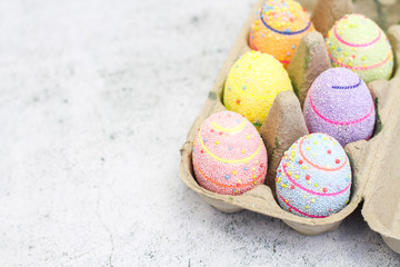 Multi-colored boiled eggs in a stewpan painted for Easter on a white background.