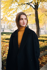 Beautiful casual girl thoughtfully looking away standing alone on autumn city street