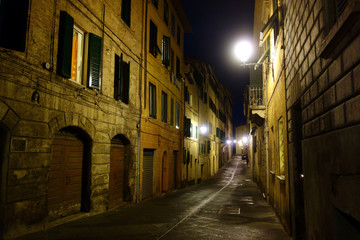 Siena by night. Illuminated street in the center of Siena from the old houses.