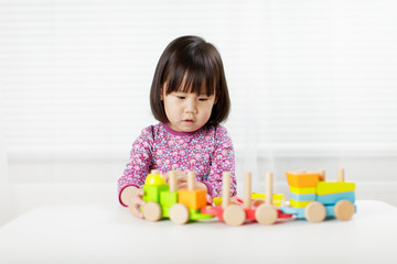 Fototapeta na wymiar toddler girl playing creative toy blocks at home against white background