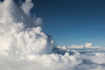 Fluffy clouds (Cumulonimbus) at high altitude over deep blue sky. Heaven, freedom, purity concept.
