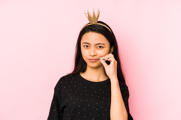 Young chinese princess woman isolated on a pink background shrugs shoulders and open eyes confused.