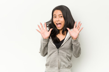 Young fitness chinese woman celebrating a victory or success, he is surprised and shocked.