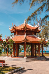 Naklejka premium Oriental-style gazebo surrounded by trees and the sea.