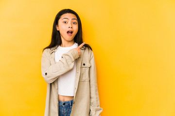 Young chinese woman isolated on a yellow background pointing to the side