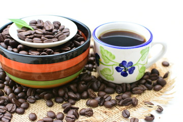 Coffee beans, accompanied by cup of hot coffee
