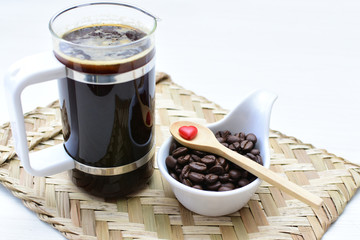 Coffee beans, accompanied by cup of hot coffee
