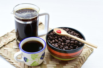 Coffee beans, accompanied by cup of hot coffee
