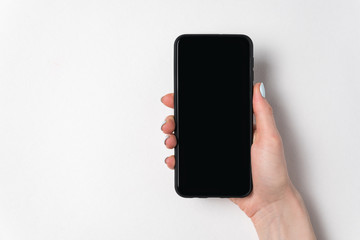 Female hand holding smartphone on white background. Blank screen. Copy space