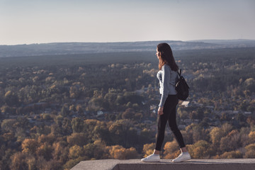 Girl stands on a hill and looks into the distance on the forest.