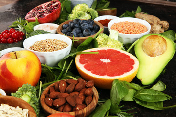 Healthy food clean eating selection: fruit, vegetable, seeds, superfood, cereals, leaf vegetable on rustic background