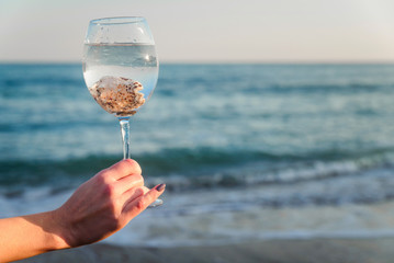 Glass with shells on a background of the sea